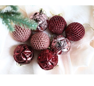 Detail of burgundy and champagne Christmas balls with glitter lattice and faceted textures
