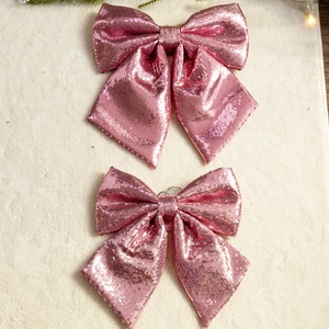 Pink sequin Christmas bow decorations on plush background for festive holiday ornament