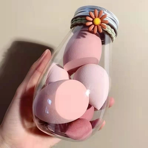 Close-up of pink makeup sponges in a glass jar with daisy hair tie decoration