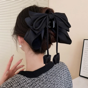 Gros plan d'une grande pince à cheveux en satin noir avec nœud et rubans élégants