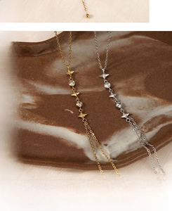 Detailed view of gold and silver Y-shaped necklaces with zircon stars on ceramic tray