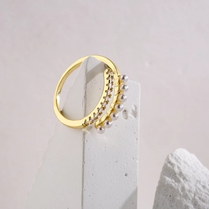 Detailed close-up of double-row 18K gold ring with pavé zircons and white pearls