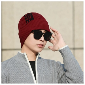 Detailed knit texture of burgundy ribbed beanie with LIKE patch on male model outdoors