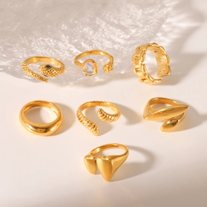 Flat lay of seven gold-plated stainless steel rings with snake and opal details