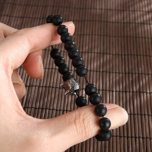 Men's matte black onyx beaded bracelet with antique silver wolf head charm on hand