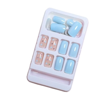 Hellblaue und rosa künstliche Nägel mit Herzmustern und Strasssteinen auf weißem Tablett