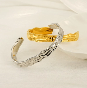 Close-up of gold and silver irregular textured open bangles with a natural lava texture