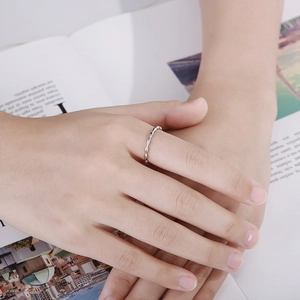 Silver minimalist wavy twisted ring shown on hand over a magazine background