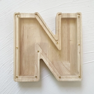 Detail of letter N wooden money box with clear acrylic panel and golden screw accents
