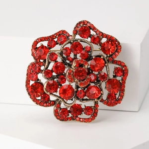 Detailed close-up of a 3D red rose brooch with sparkling rhinestones and gold alloy petals