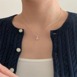 Close-up of a delicate C-shaped zircon pendant necklace on a model's neck