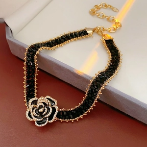 Detail of a black crystal beaded bracelet with a rhinestone flower and golden lobster clasp
