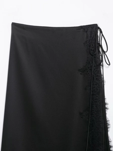 Dettaglio gonna midi in raso nero con bordo in pizzo e chiusura con lacci laterali