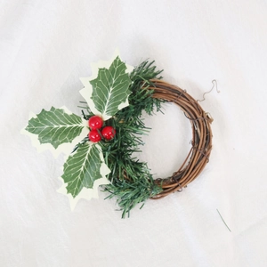 Détail d'un anneau de bougie de Noël avec baies rouges, houx et base de vigne tressée