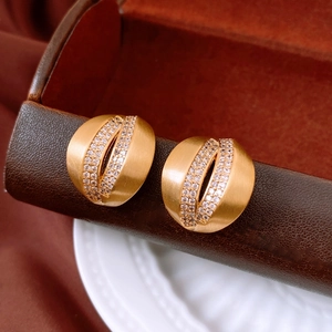 Macro shot of gold-plated C-shape stud earrings with matte finish and micro zircon stones