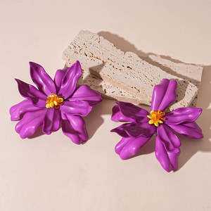 Macro shot of 3D purple acrylic flower earrings with yellow beaded centers on stone