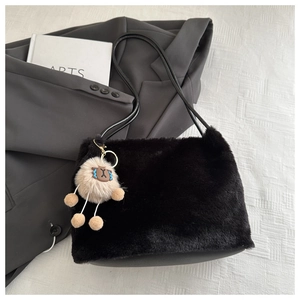Detail of black faux fur tote bag with plush sheep charm and slim leather strap