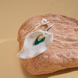 Macro detail of irregular petal-shaped ring with green enamel and white pearls