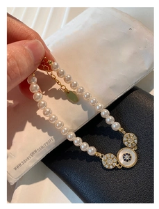 Détail du bracelet en perles plaqué or 18k avec œil bleu et breloques en cristal