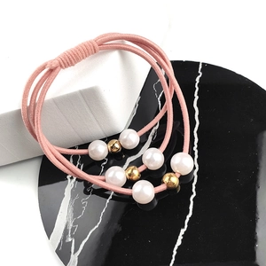 Gros plan d'un chouchou rose avec perles blanches et billes dorées sur marbre
