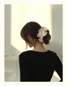 Gros plan d'un chouchou géant blanc avec bord ondulé rouge sur cheveux attachés
