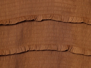 Detail of brown fabric with elastic smocking stitching and layered ruffle edge texture