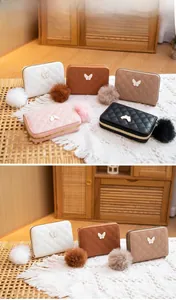 Close-up of quilted leather purse with butterfly metal piece and fluffy pom-pom charm