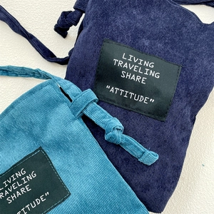 Close-up of corduroy phone bags showing fabric texture and square woven logo labels