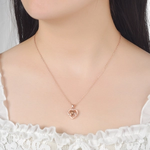 Detailed view of rose gold heart pendant with projection stone on neck of a model