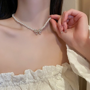 Detail of elegant bow necklace with pearls and sparkling diamonds worn by a model
