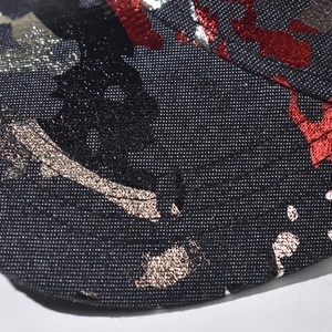 Macro shot of baseball cap fabric with red and metallic gold industrial spray print
