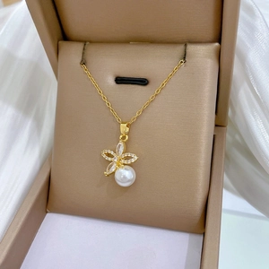 Detail of gold floral pendant featuring sparkling zircons and a white lustrous pearl charm