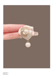 Détail d'une broche camélia avec pétales en émail, perles et métal doré brillant