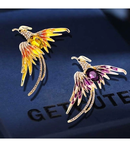 Detailed macro view of rhinestone phoenix brooches in yellow and purple enamel finish