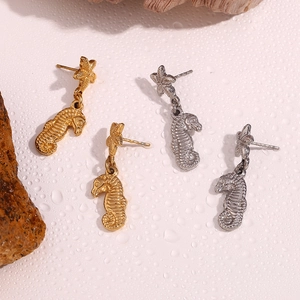 Macro view of seahorse and starfish dangle earrings in polished gold and silver finishes