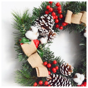 Macro detail of Christmas wreath with pine cones, red berries, and white cotton balls