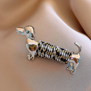 Macro shot of silver metal dachshund brooch with colorful braided rope detail on satin