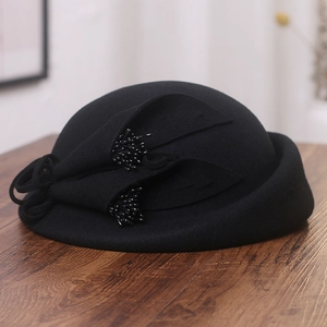 Détail du chapeau élégant en feutre noir avec fleur en tissu 3D et centre perlé