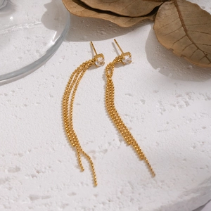 Primo piano di orecchini a nappa placcati oro 18K con zircone su marmo