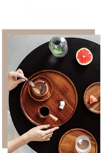Close-up of round wooden serving trays with natural grain on a dark coffee table setting