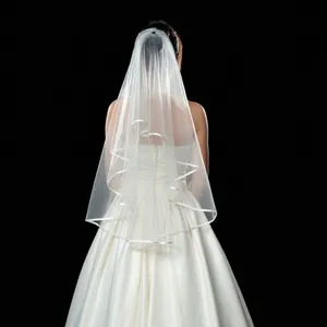 Elegant white double-layer bridal veil with satin ribbon edge against a black background