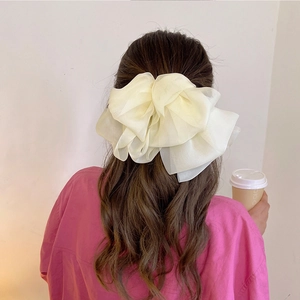 Close-up of a large pale yellow organza bow hair clip on a model's head