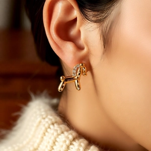 Detailed close-up of 18k gold plated horse stud earring with zircon on model ear