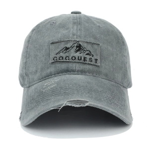 Macro view of distressed grey cotton baseball cap featuring GOQUEST mountain patch