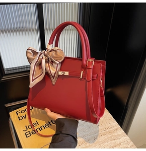 Detailed view of red leather tote bag with printed silk scarf handle and gold hardware