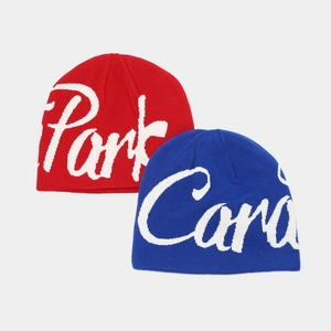 Detail of red and blue knit beanies with white cursive lettering in retro street style