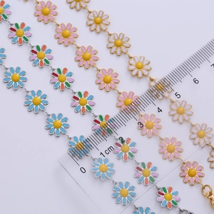 Macro shot showing 1cm colorful enamel daisy charms on 18k gold plated chains with ruler