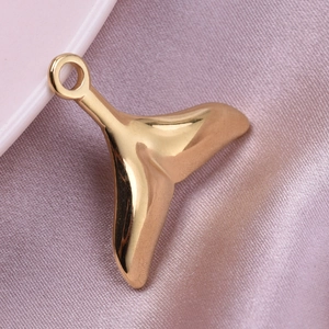 Macro shot of 18k gold plated stainless steel fishtail pendant on pink silk background