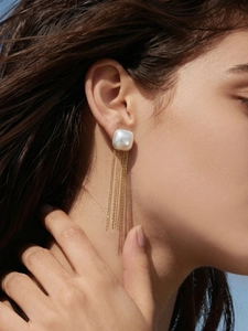 Detailaufnahme der eleganten Goldketten-Quasten und weißen Perle am Ohrläppchen