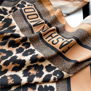 Macro shot of silk satin scarf showing leopard print pattern and soft fabric texture